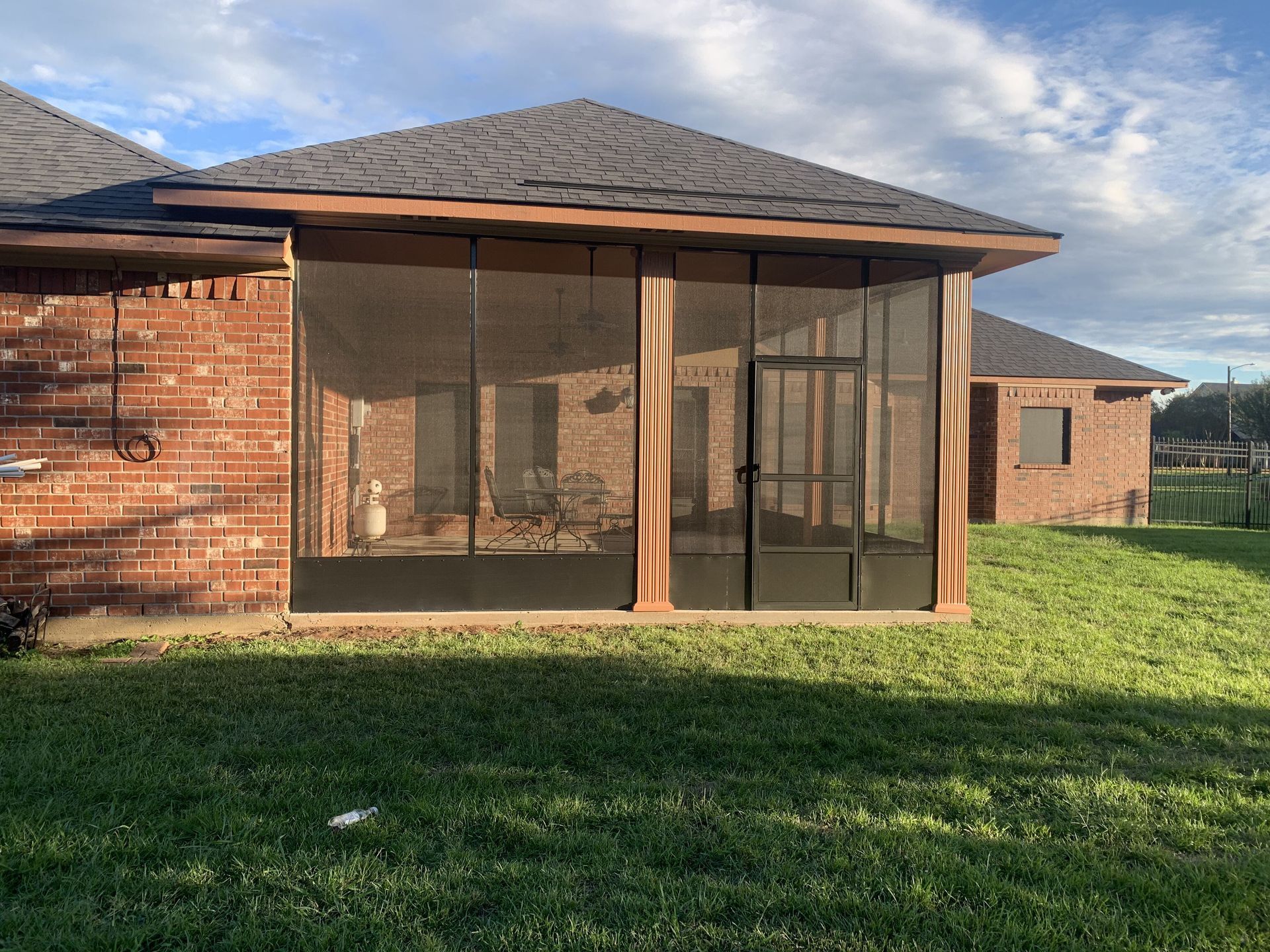 A brick house with a screened in porch in the backyard.