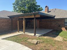 A brick house with a covered patio in front of it.