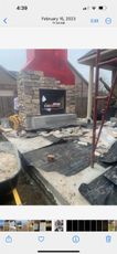 A stone fireplace is being built in the backyard of a house.