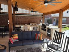 A patio with a couch , rocking chairs , and a ceiling fan.