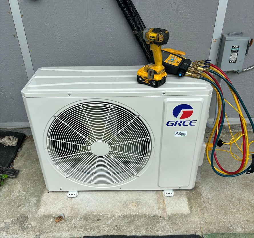 GREE air conditioner unit outdoors, with tools. Hoses are attached, yellow drill on top.