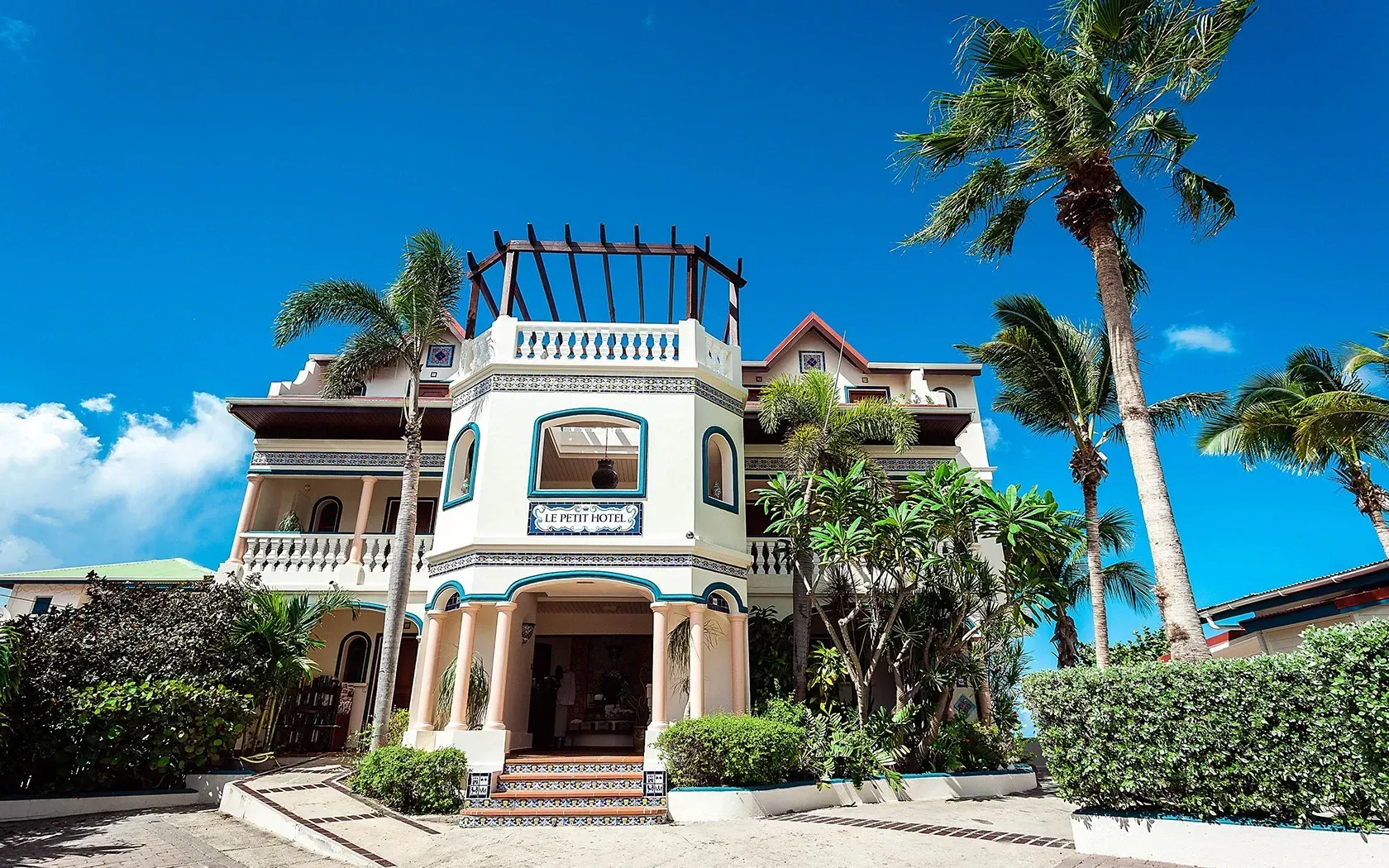 Elegant light-colored building with ornate design, palm trees, and blue sky.