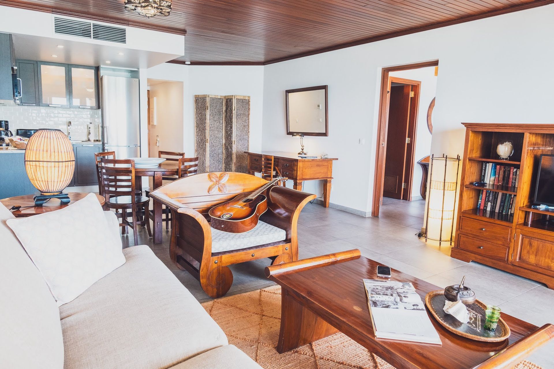 ONE BEDROOM SUITE Living room with wood furniture, white walls, and a view of the kitchen.
