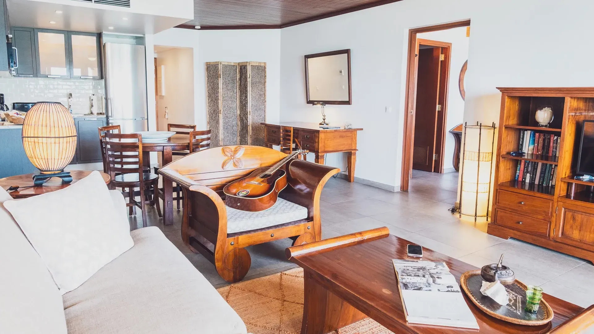 Living room with wooden furniture, white sofa, and a view into the kitchen.
