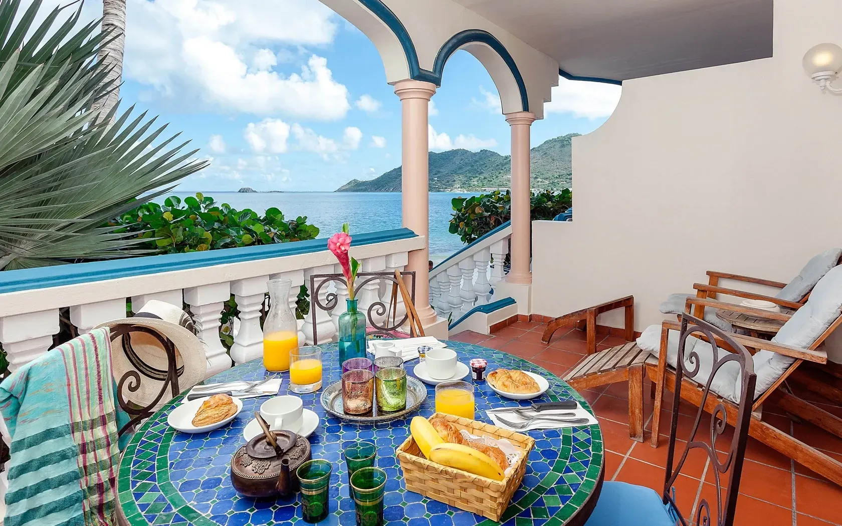 Balcony breakfast: table with food, ocean view, blue and white decor.