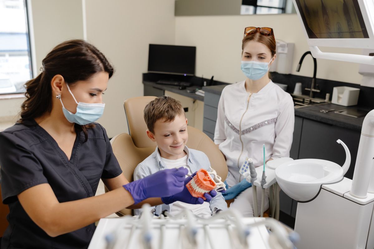 A woman is sitting in a dental chair talking to a dentist.
