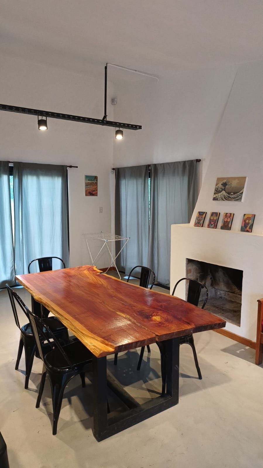Comedor con mesa de madera, sillas negras y chimenea.