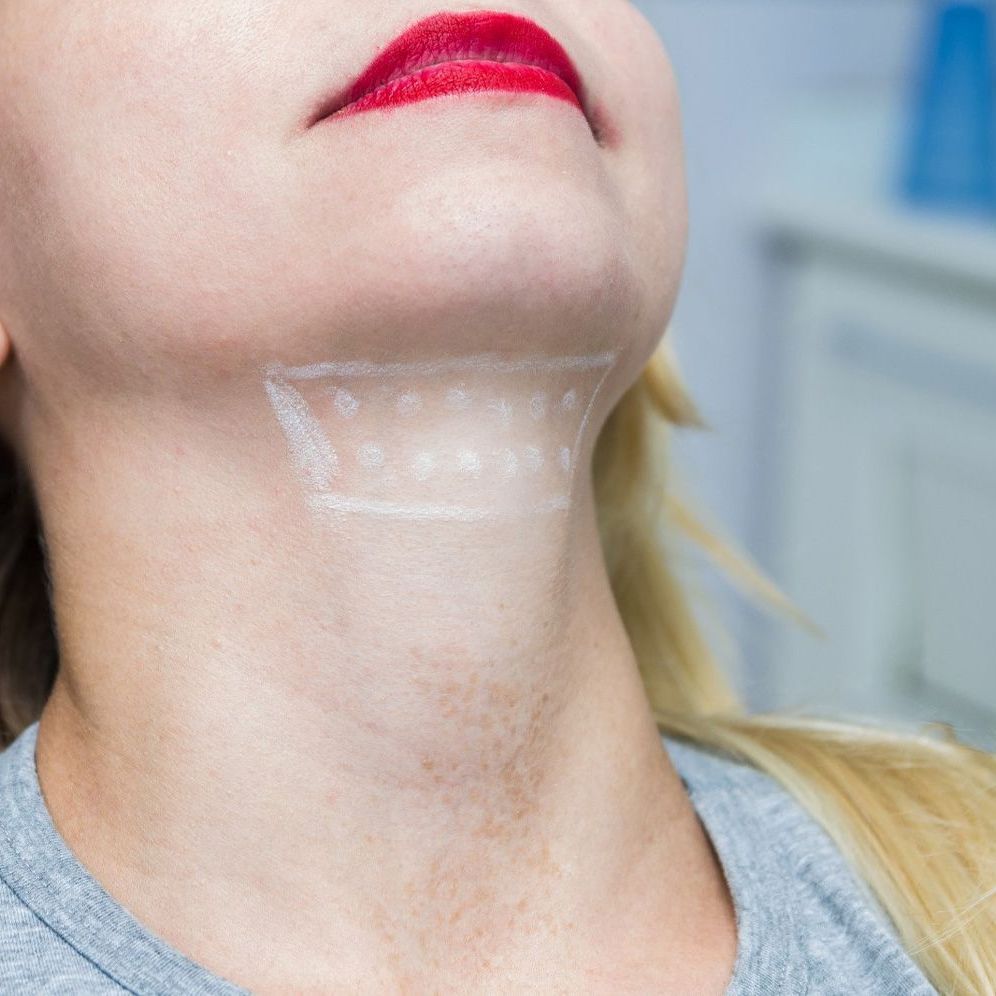 A woman with red lipstick is looking up at her neck.