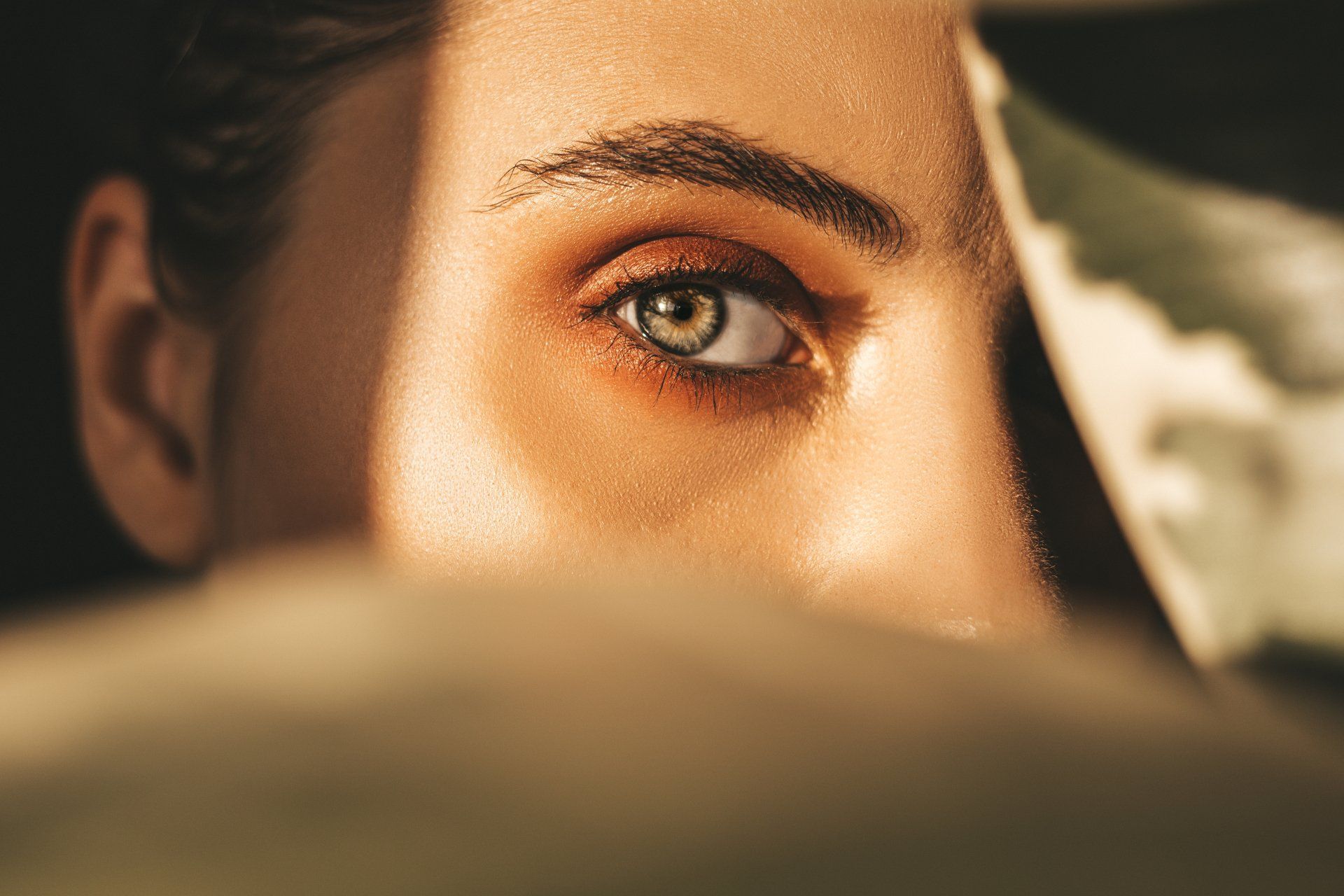 A close up of a woman 's eye looking out of a mirror.