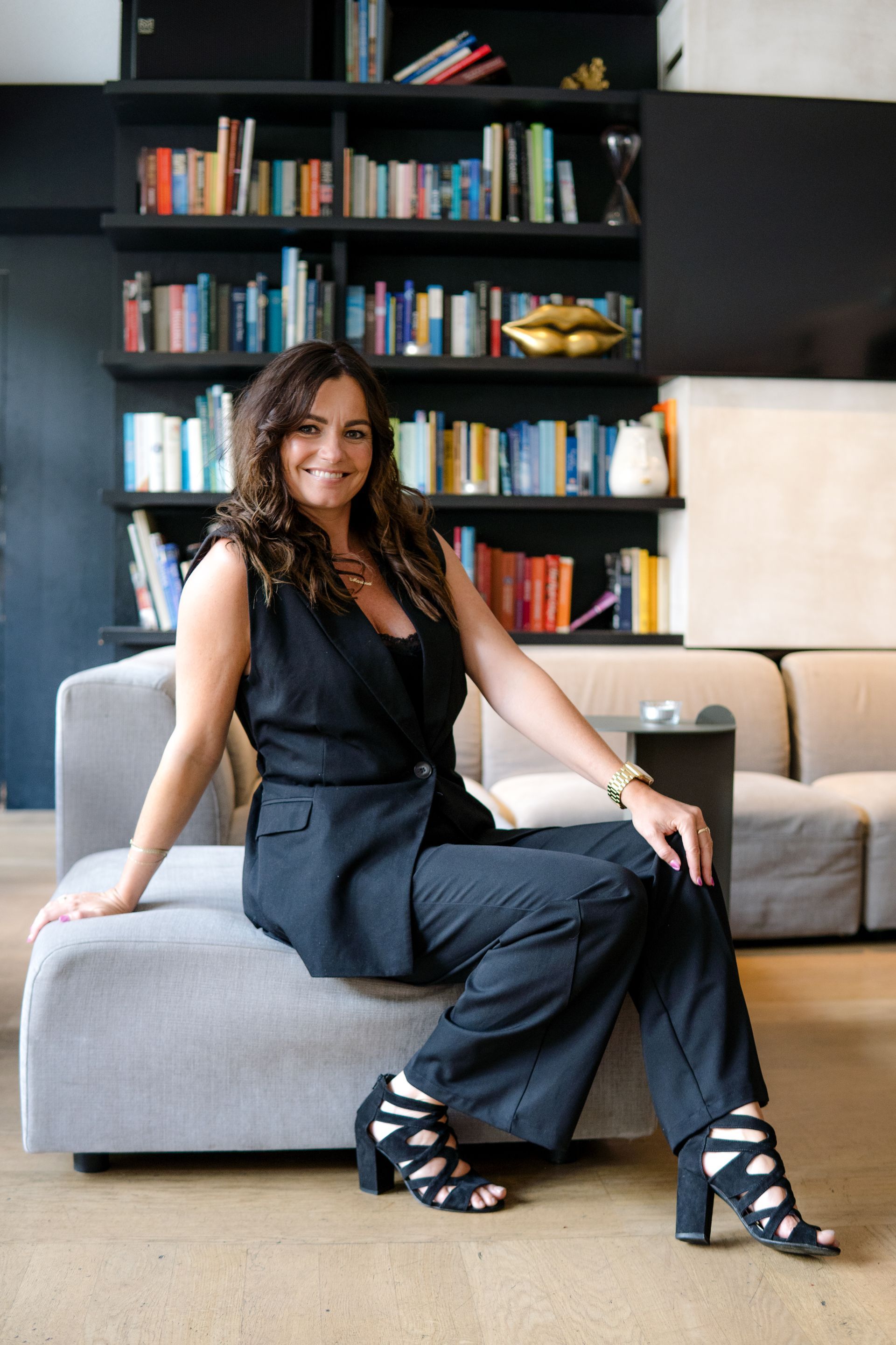 Een persoon zit glimlachend op stenen trappen voor twee donkere deuren met het opschrift