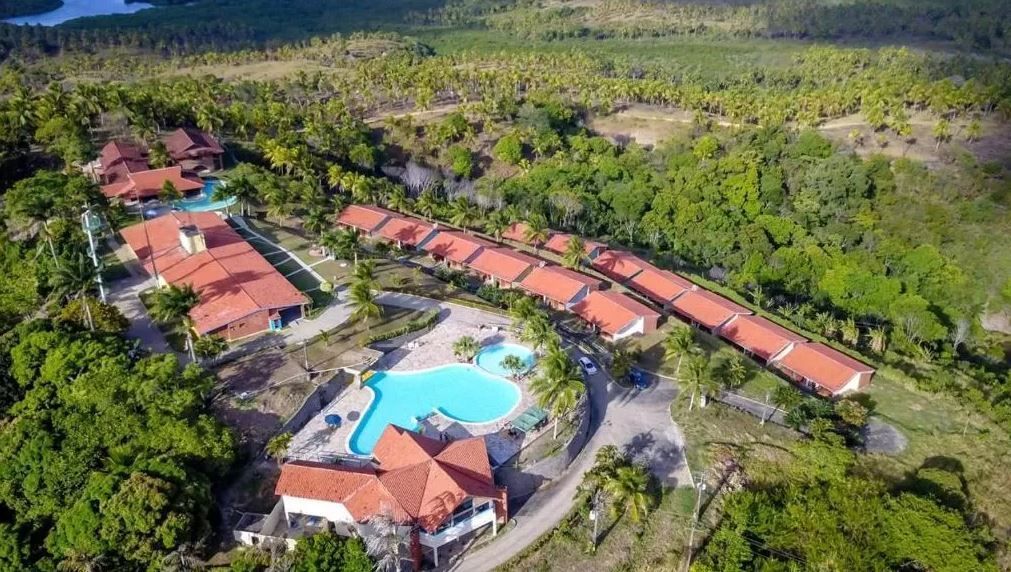 Vista aérea de um resort com piscina cercada por árvores.
