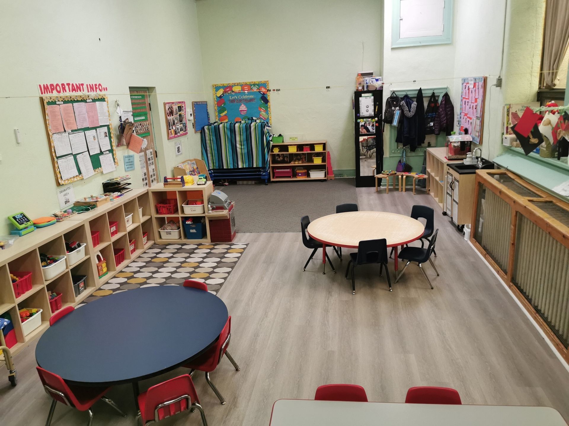 inside of preschool daycare filled with round tables and chairs and carpets