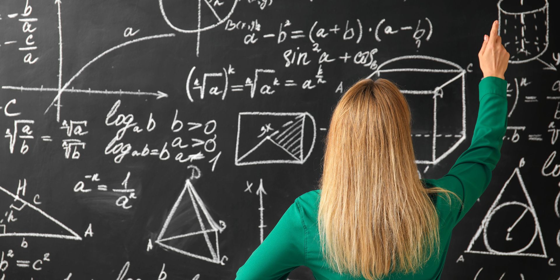 A woman is writing on a blackboard with her hand.