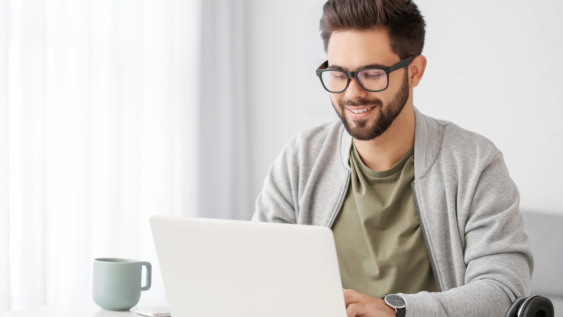 A man is sitting at a table using a laptop computer.