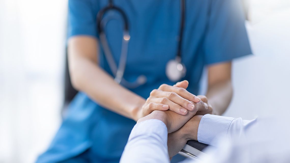 A nurse is holding a patient 's hand in a hospital.