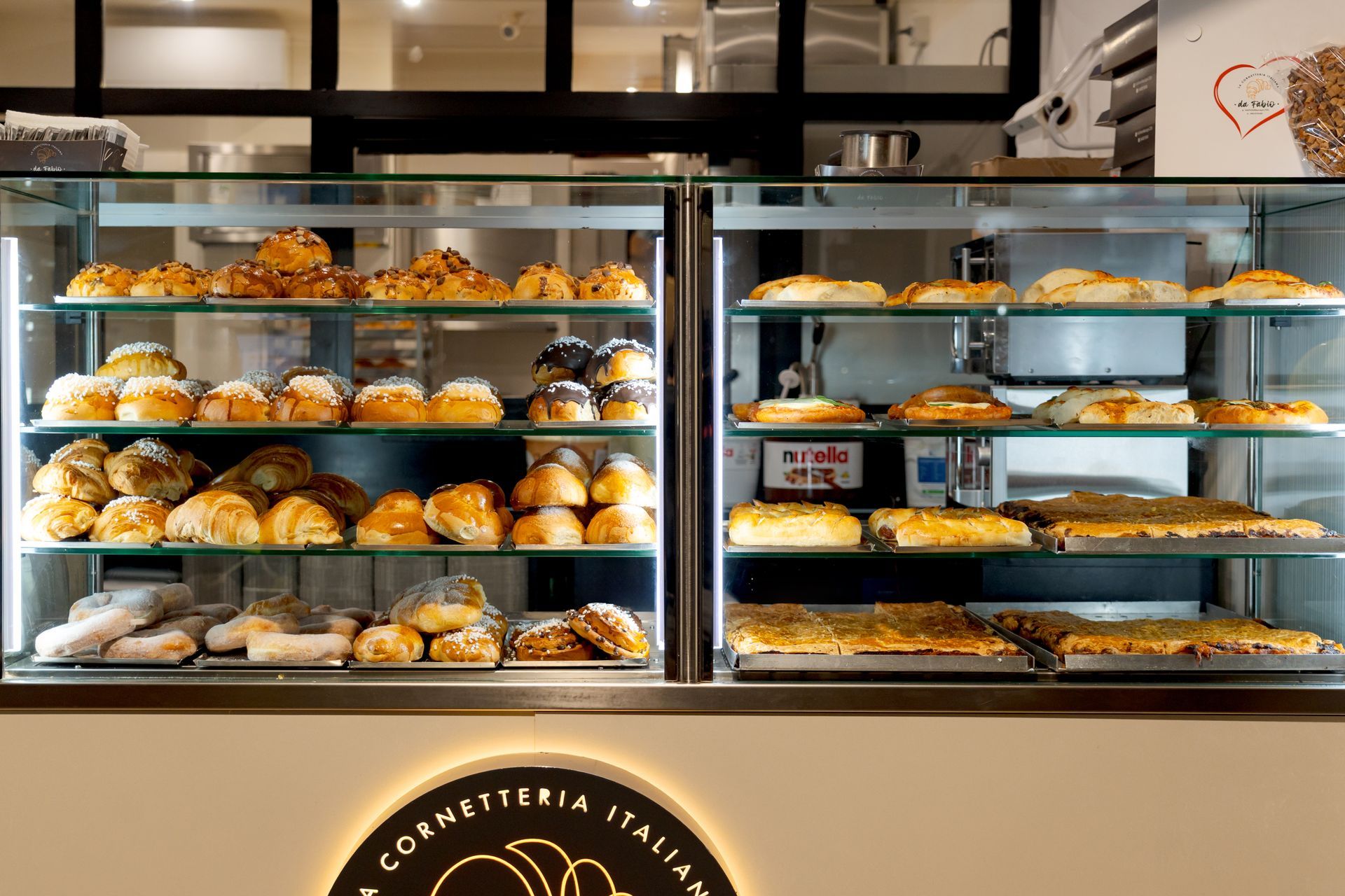 Pasticcini esposti in una vetrina di vetro, decorati con frutta fresca e panna.