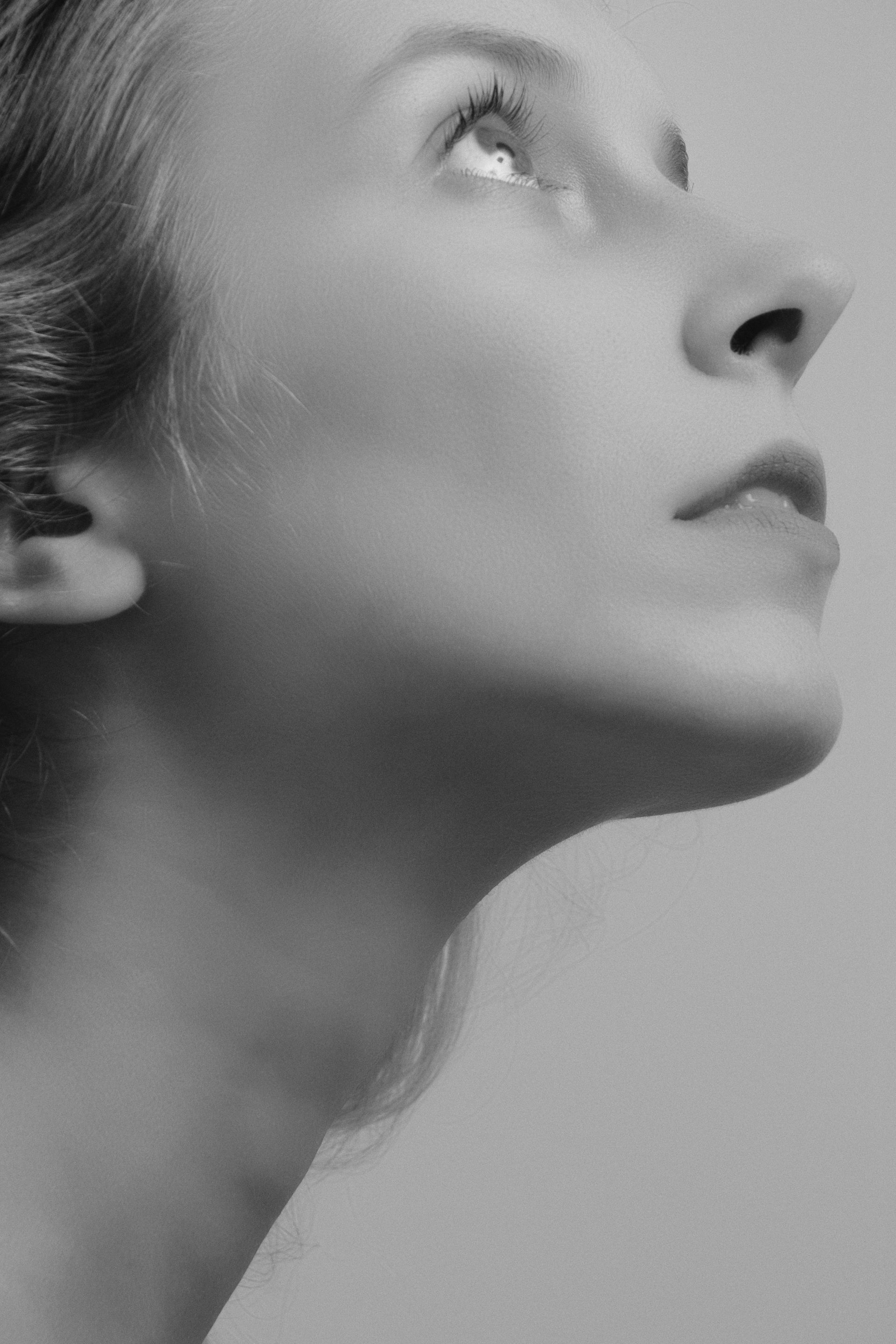 Woman looking upwards in black and white, profile view.