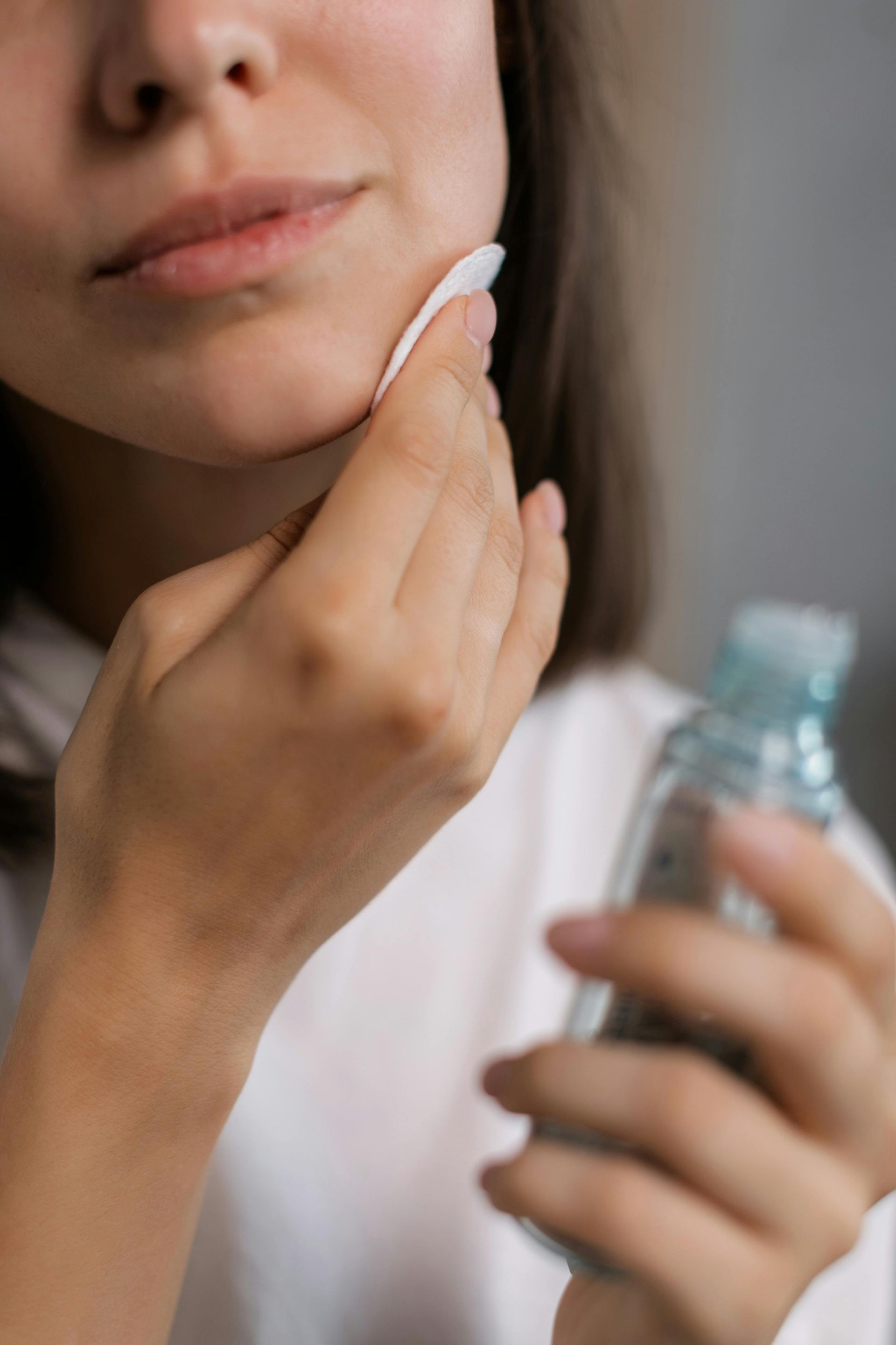 Person applying skincare product with cotton pad.