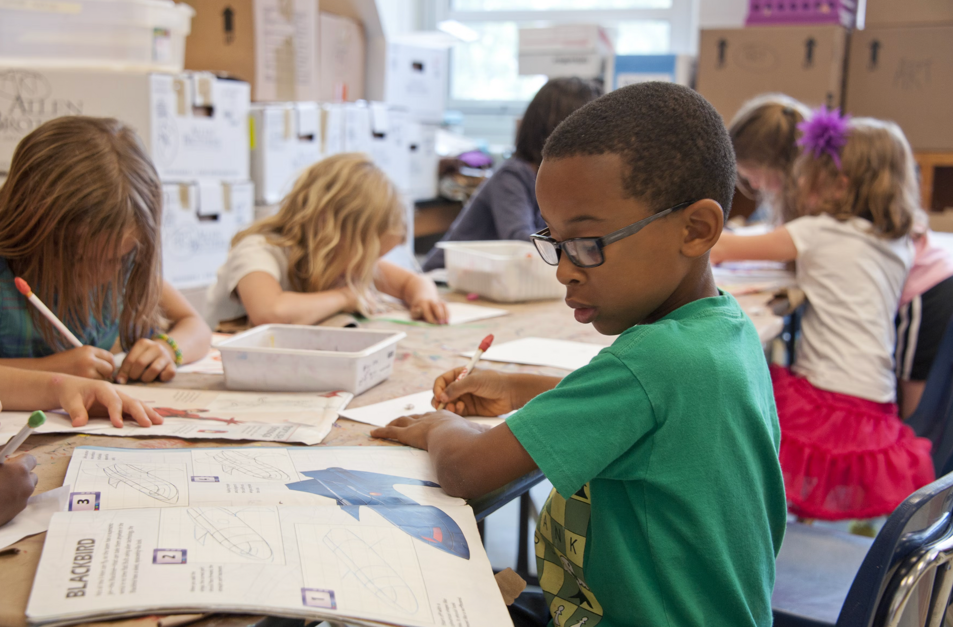 A group of children are sitting at a table in a classroom.