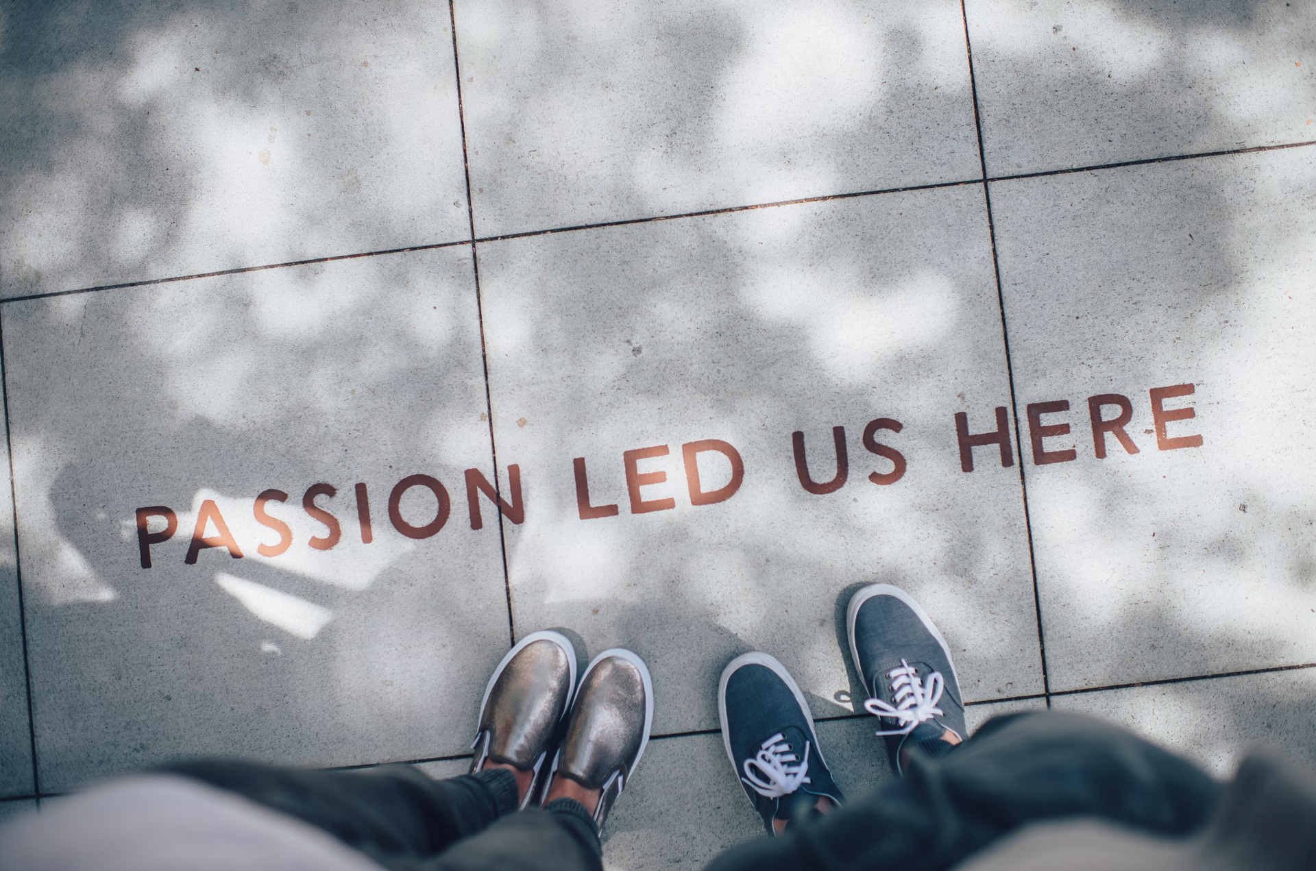 Two people are standing on a sidewalk with the words passion led us here written on the ground.