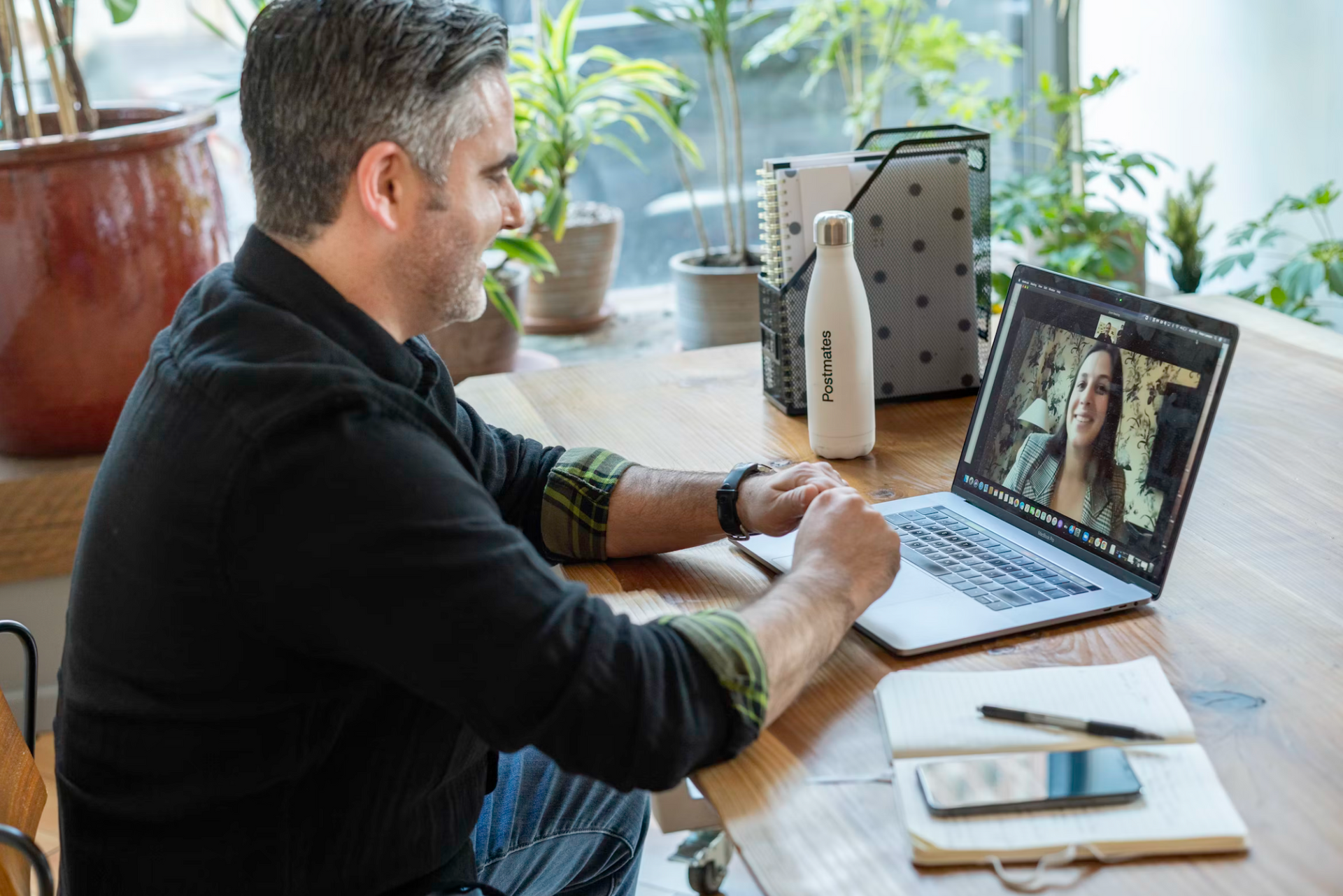 A man is sitting at a desk using a laptop computer on a long-distance Zoom call.