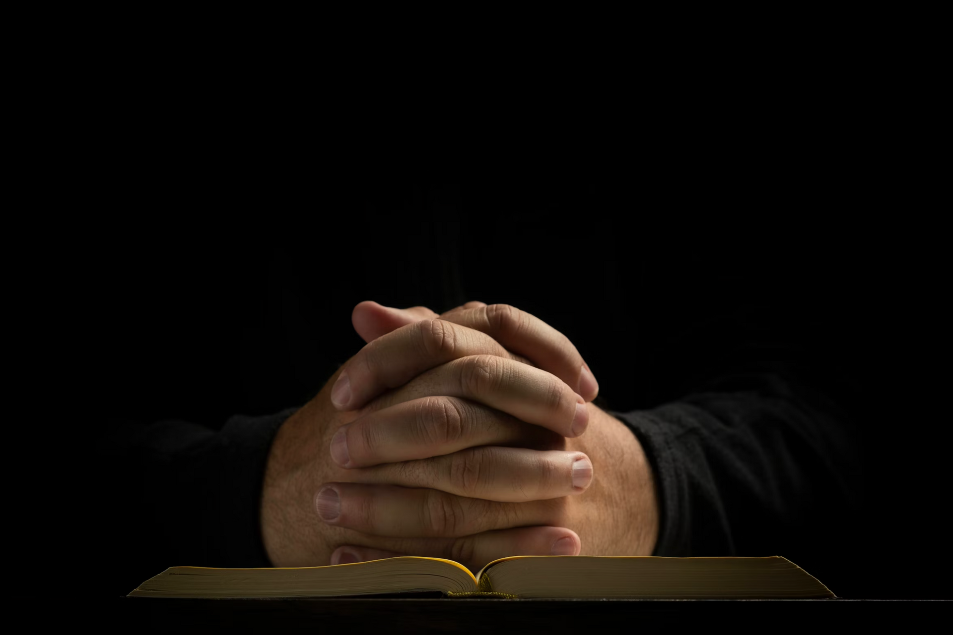 praying hands over a bible