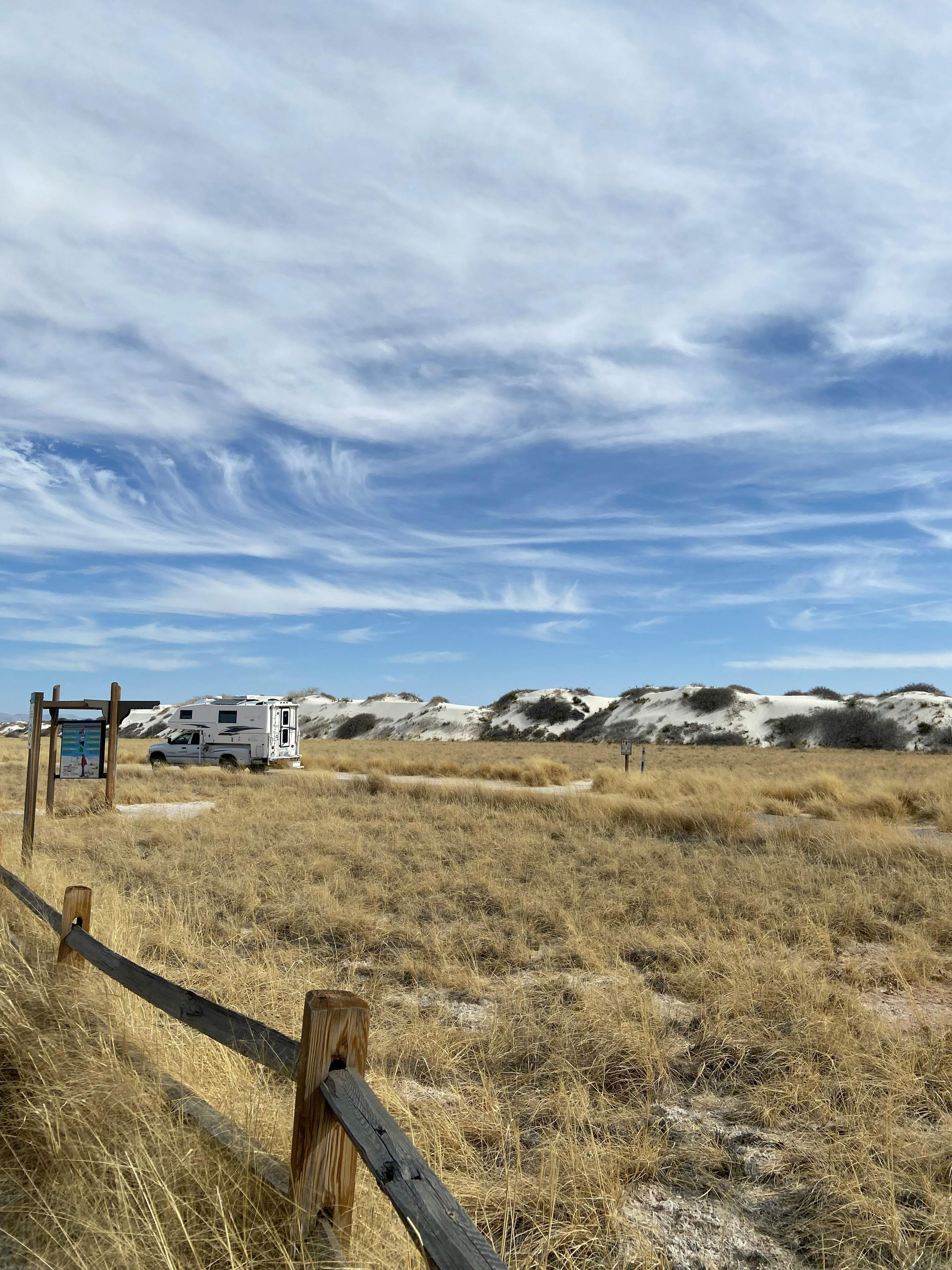 A fence surrounds a field with a rv parked in the distance.