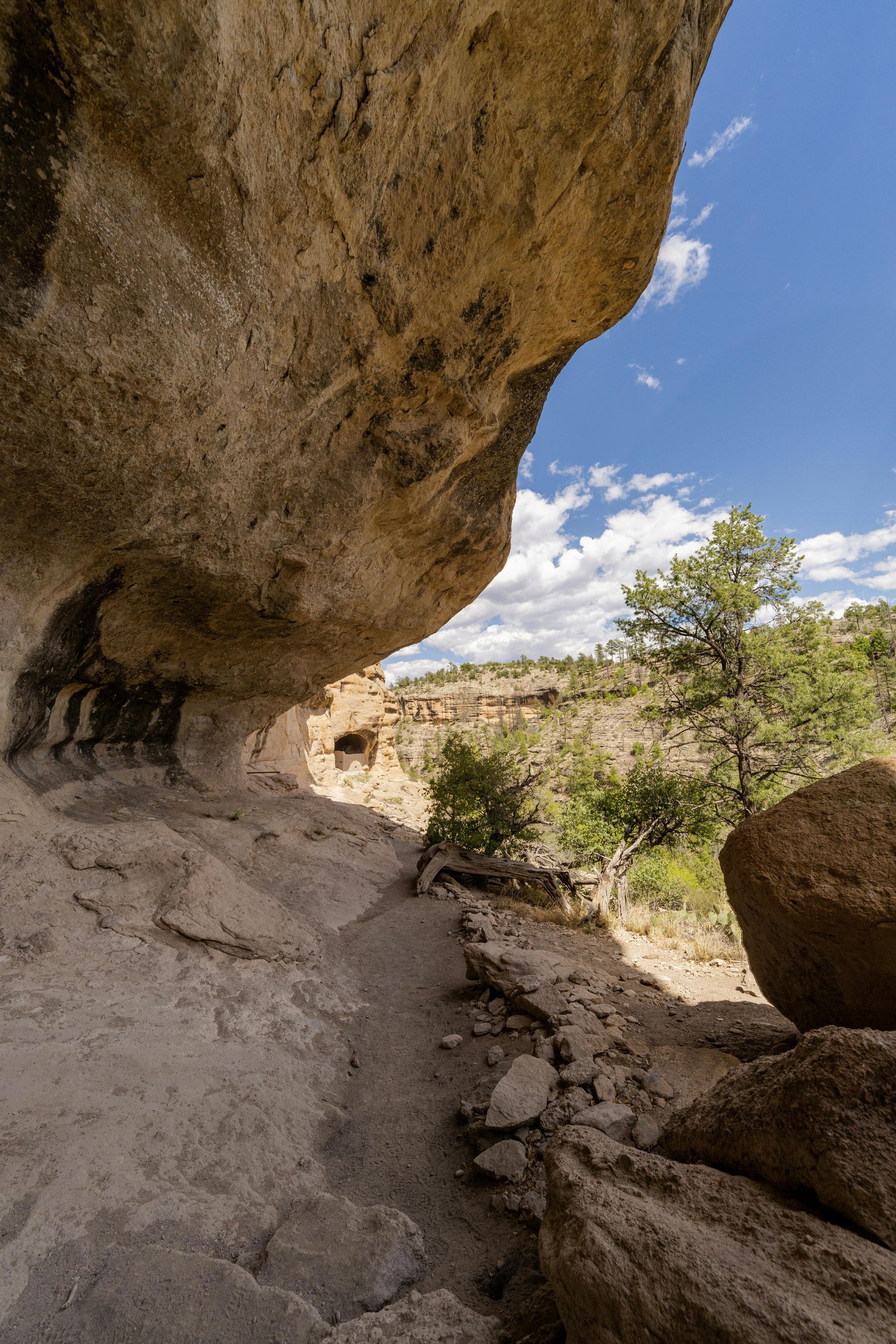 A path going under a large rock in the desert.