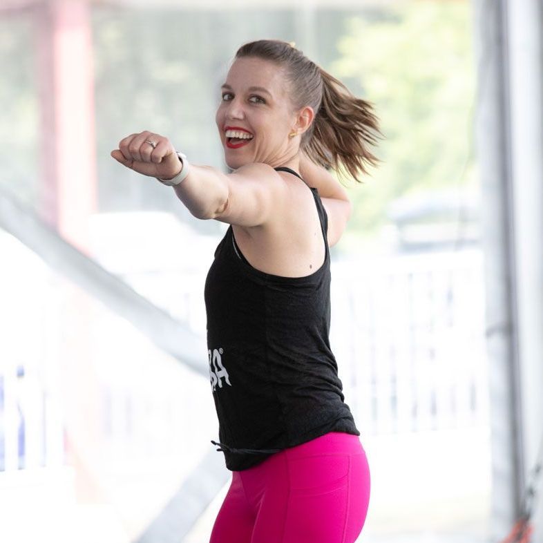 A woman in a black tank top and pink pants is smiling