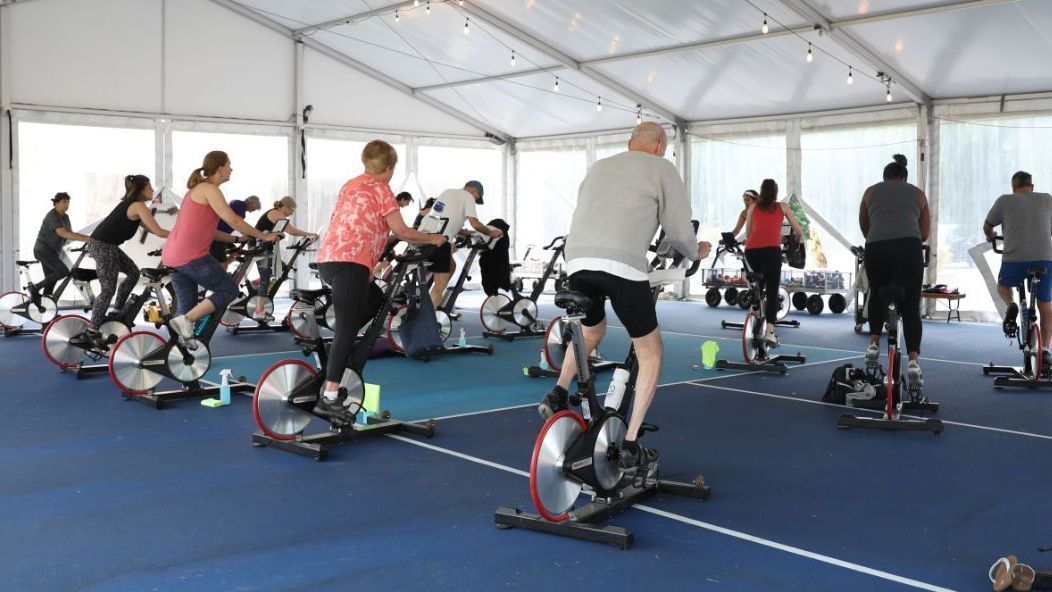 A group of people are riding exercise bikes in a gym.