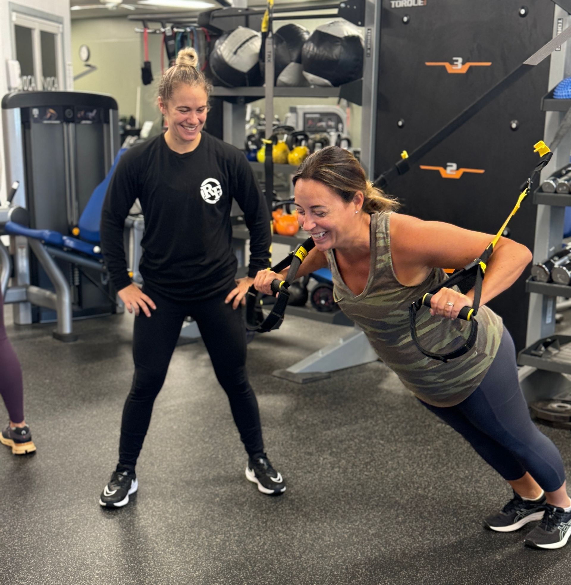 A trainer is coaching a woman on TRX