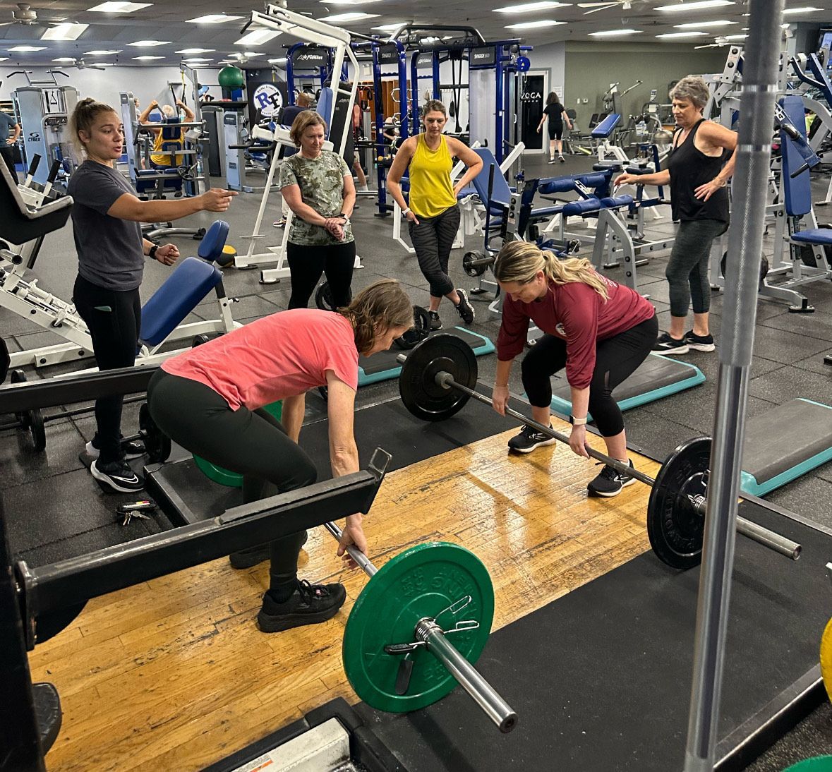 Members using the strength training section to perform deadlifts on a squatting platform.