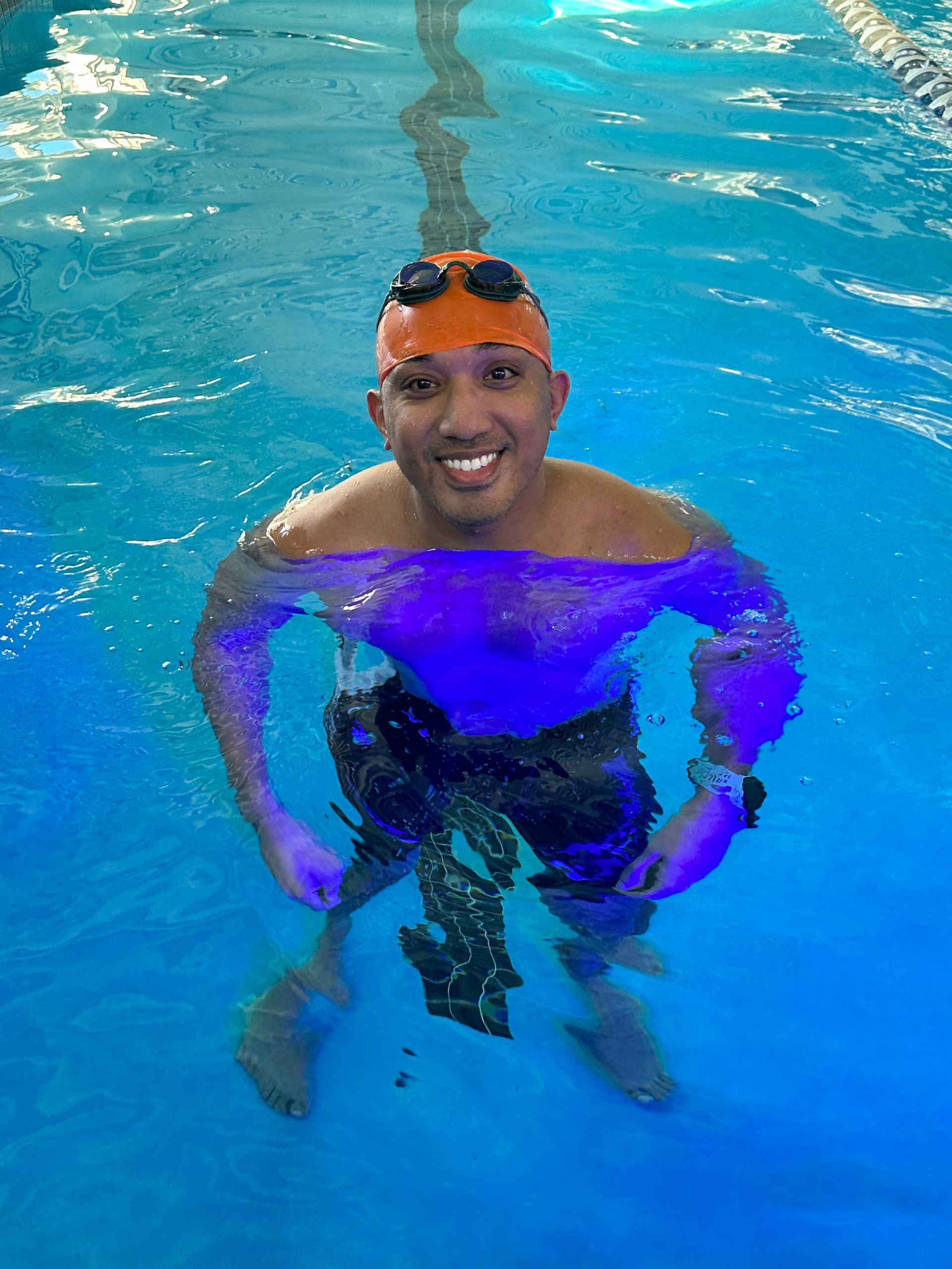 A man is swimming in a pool wearing a swim cap and goggles.
