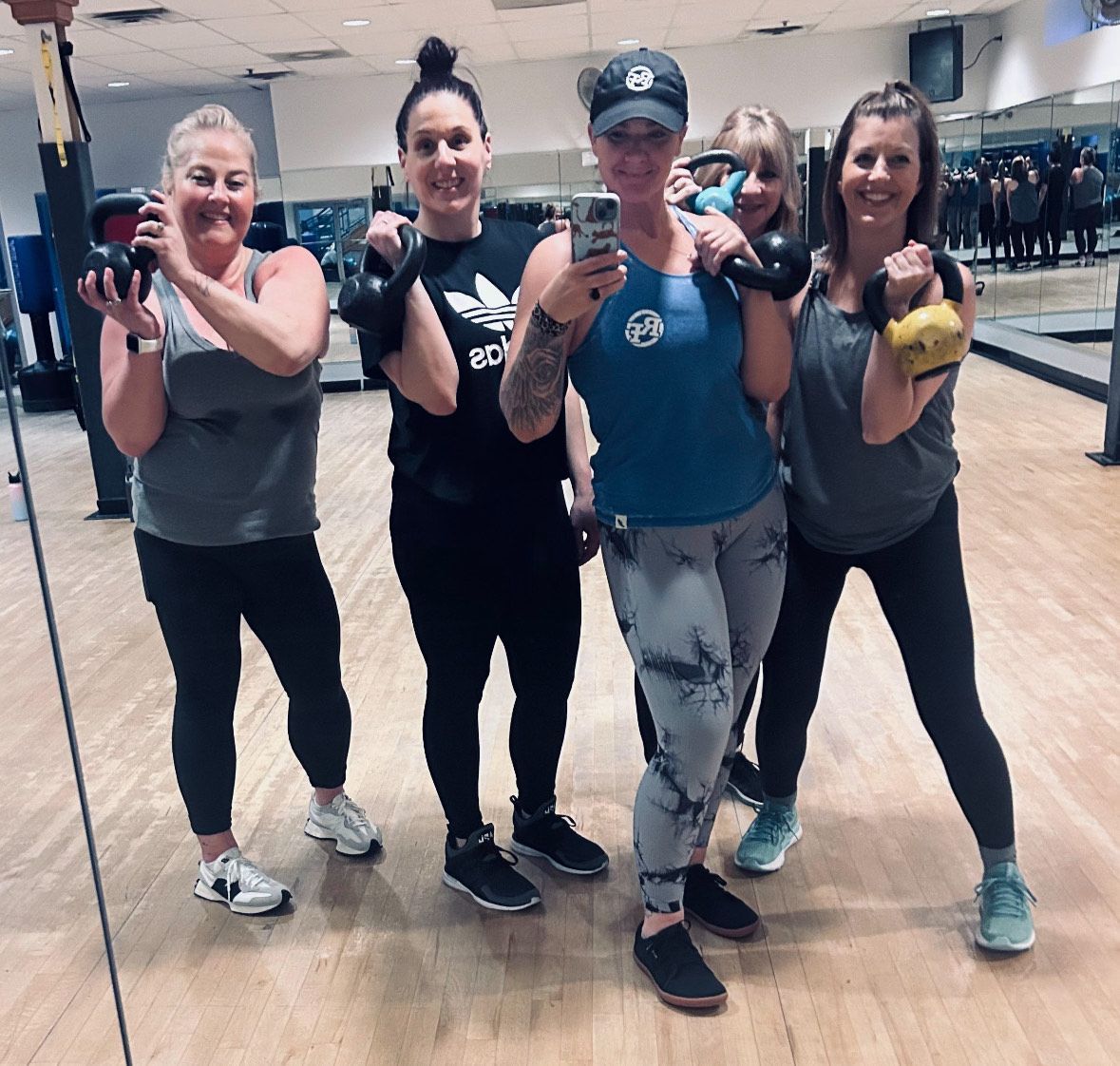 A group of women are posing for a picture in front of a mirror