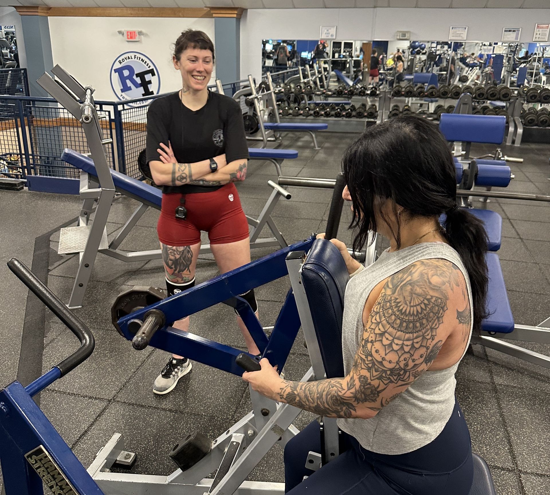 A woman is lifting weights in a gym with her personal trainer.