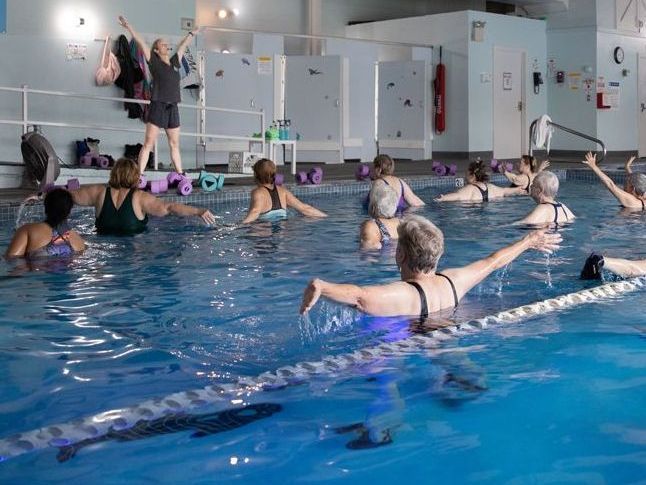 A group of women are doing exercises in a swimming pool.