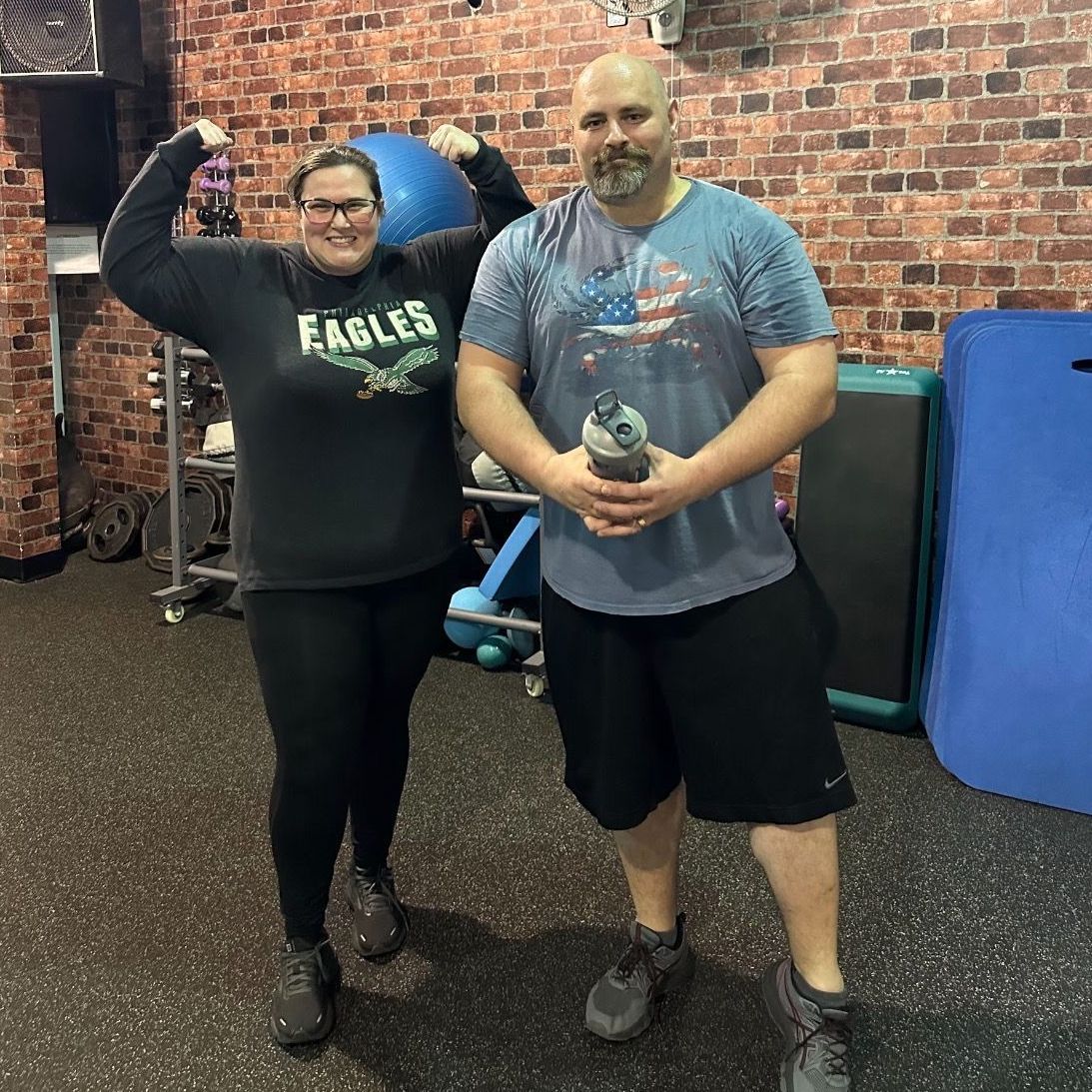 A man and a woman are posing for a picture in a gym.