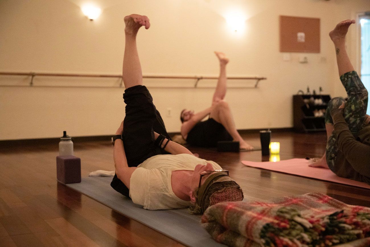 A group of people are laying on yoga mats in a room.