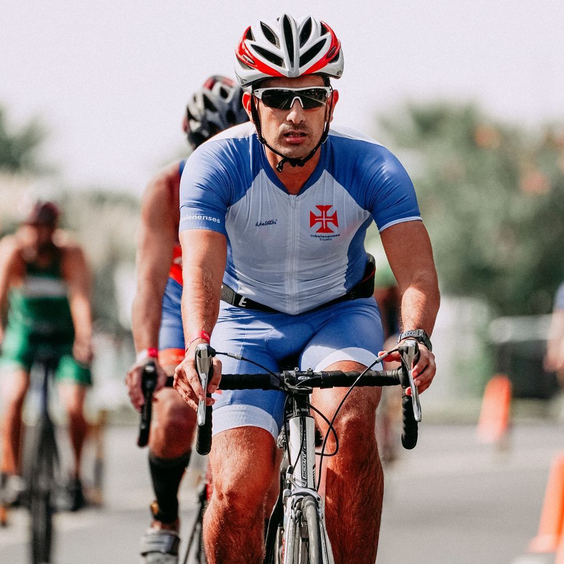 A man wearing a helmet and sunglasses is riding a bike
