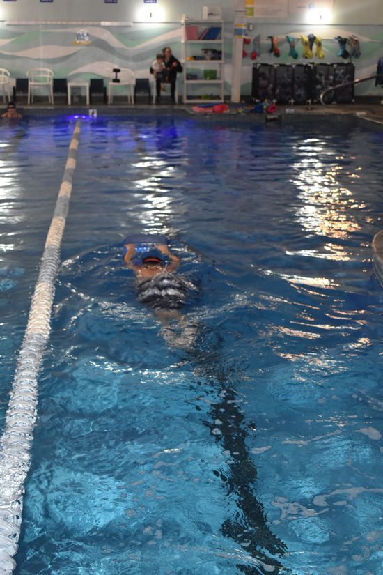 A person is swimming in a large indoor swimming pool.