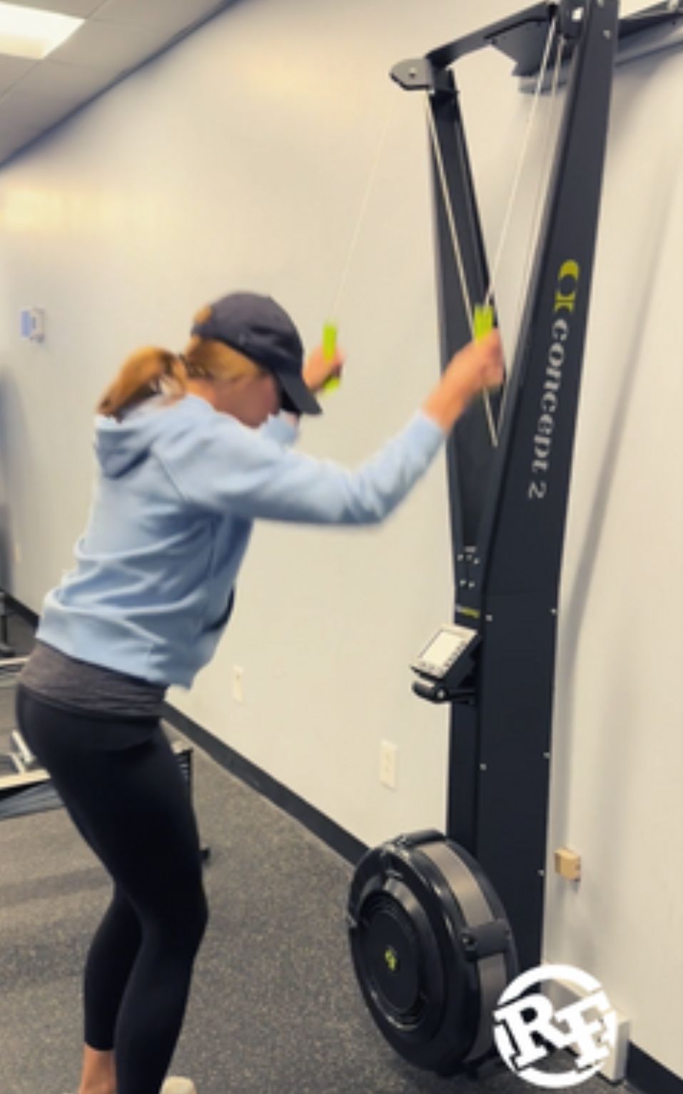 A woman is using a concept 2 machine in a gym