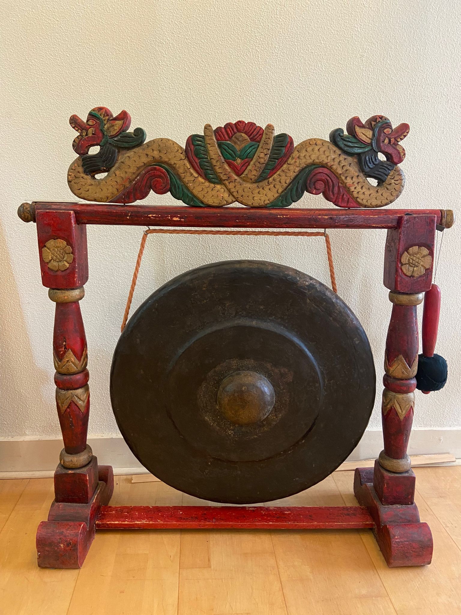Een gong staat op een houten standaard op een houten vloer.