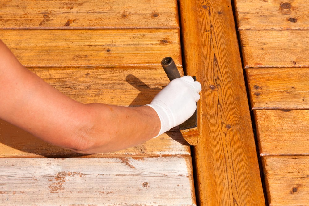 a person is painting a wooden deck with a hammer .