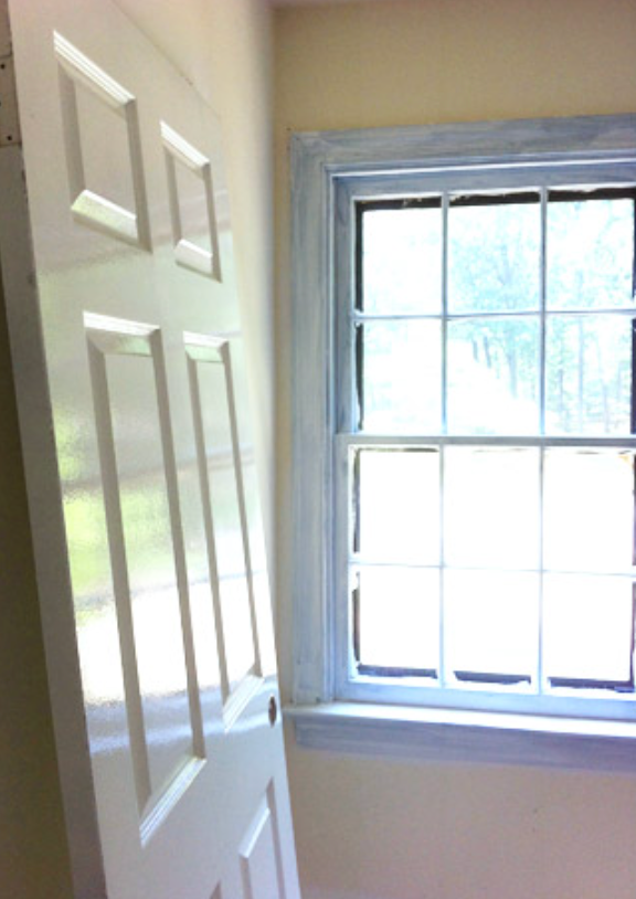 A person is painting a door frame with a brush.