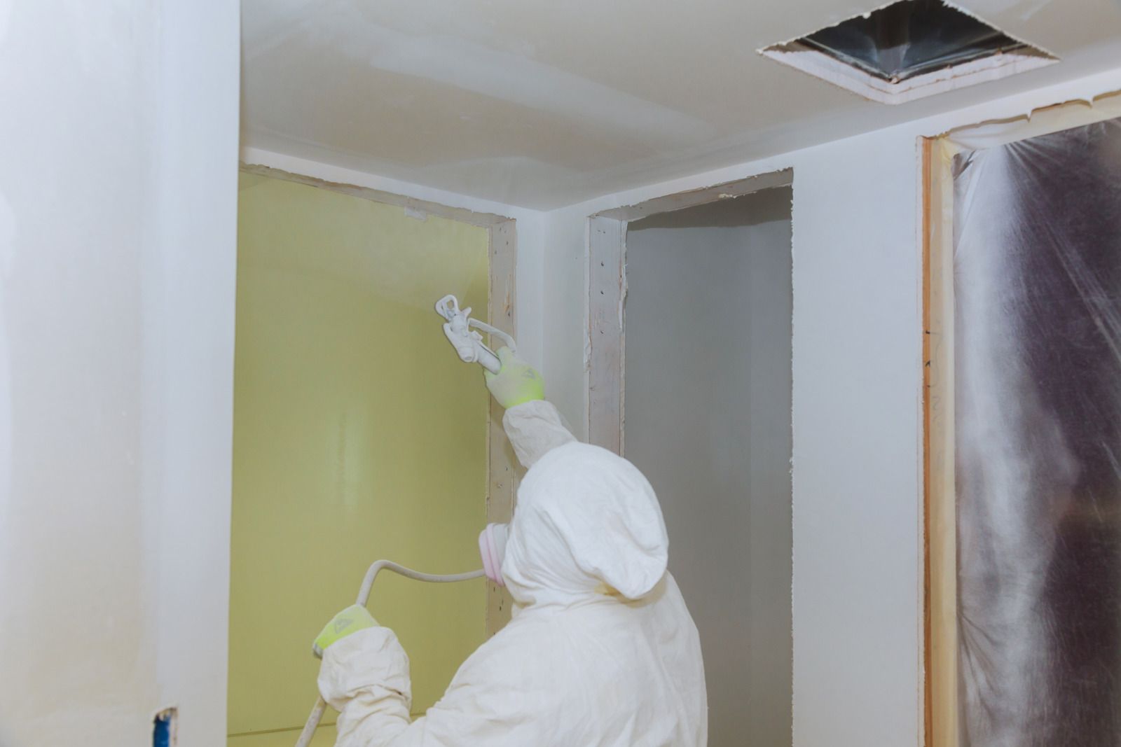 A person is spraying paint on a wall in a room.