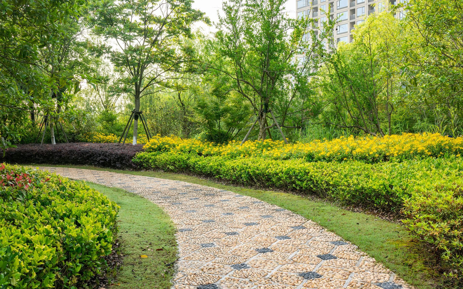 A stone path in a park surrounded by trees and bushes.