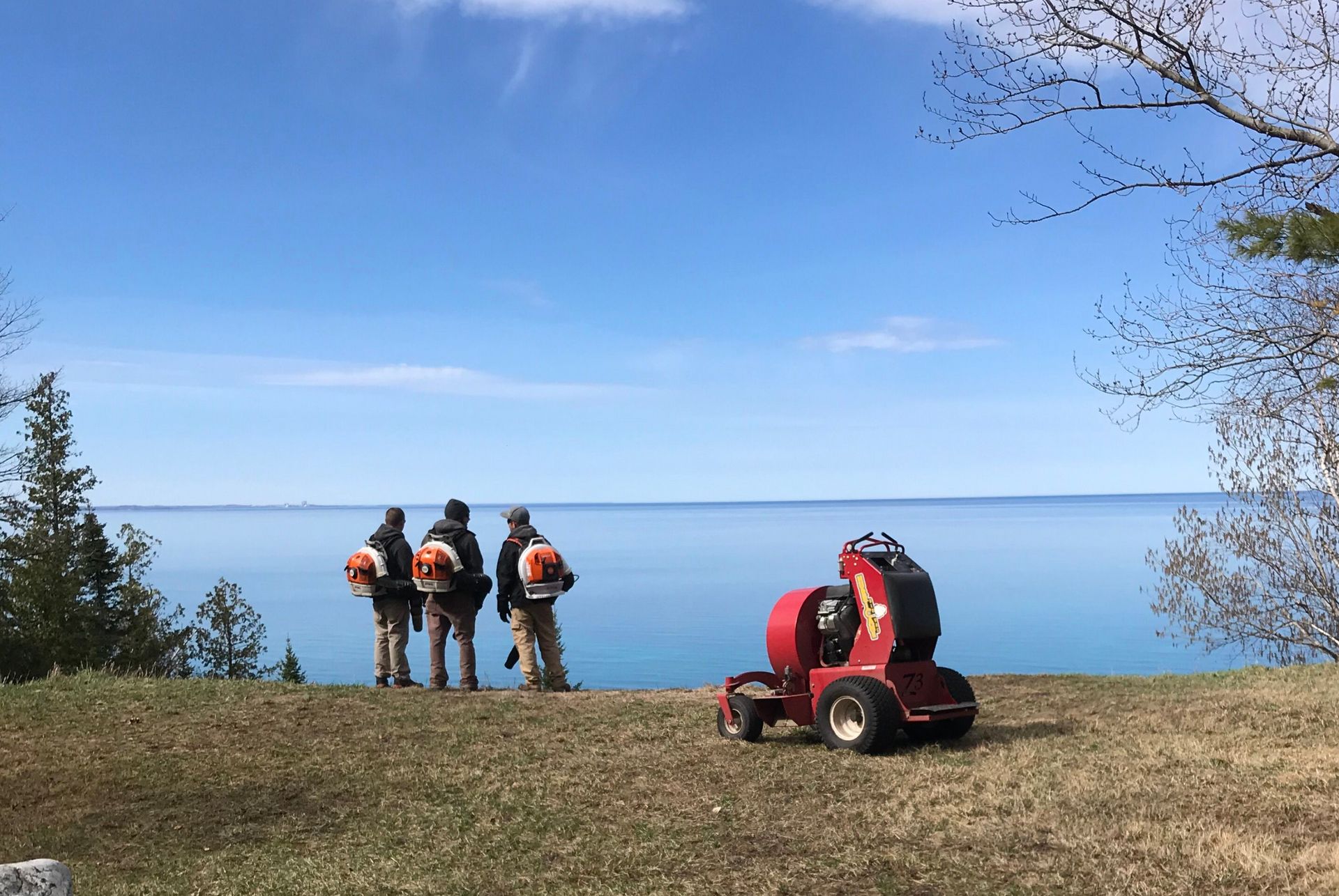 A man is rolling up rolls of turf in a lawn.