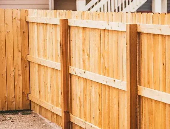 A man is installing a wooden deck with a drill.