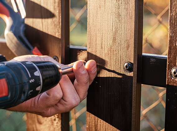 A man is installing a wooden deck with a drill.