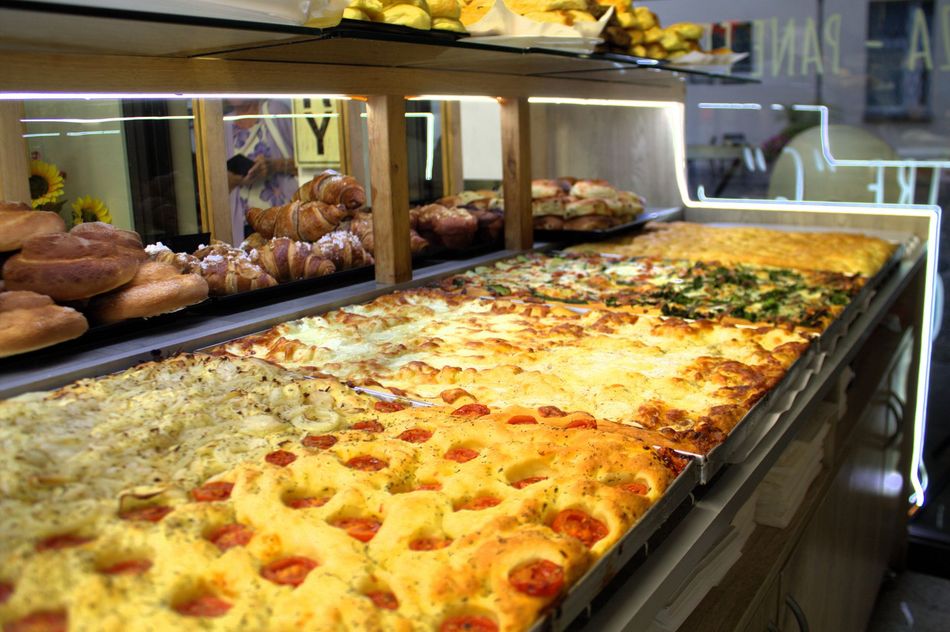 Vetrina con vari tipi di focacce e prodotti da forno in stile panetteria.